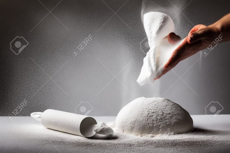 Photo de farine et de mains d'hommes avec des éclaboussures de farine. cuisson du pain. pétrir la pâte. isolé sur fond sombre. espace vide pour le texte