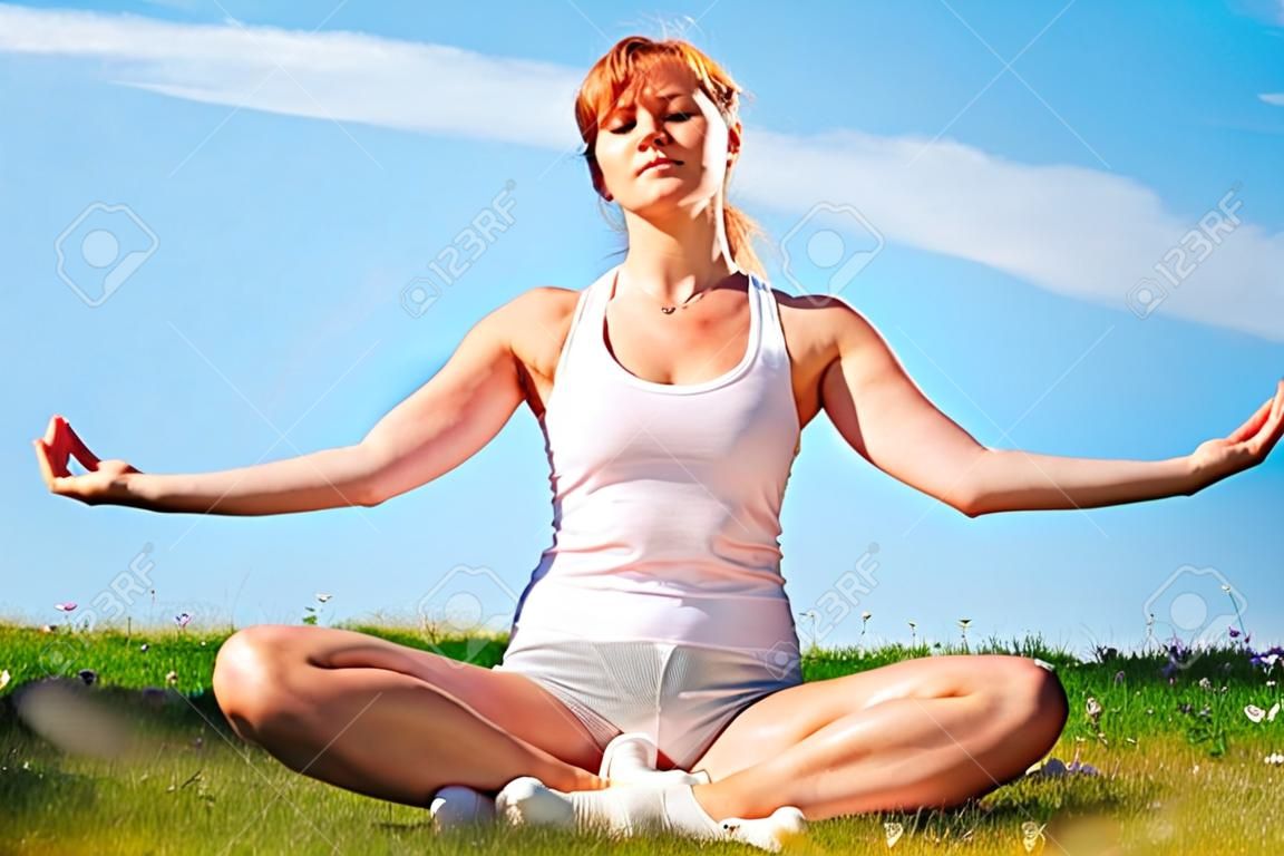 young happy girl training yoga on sunny meadow