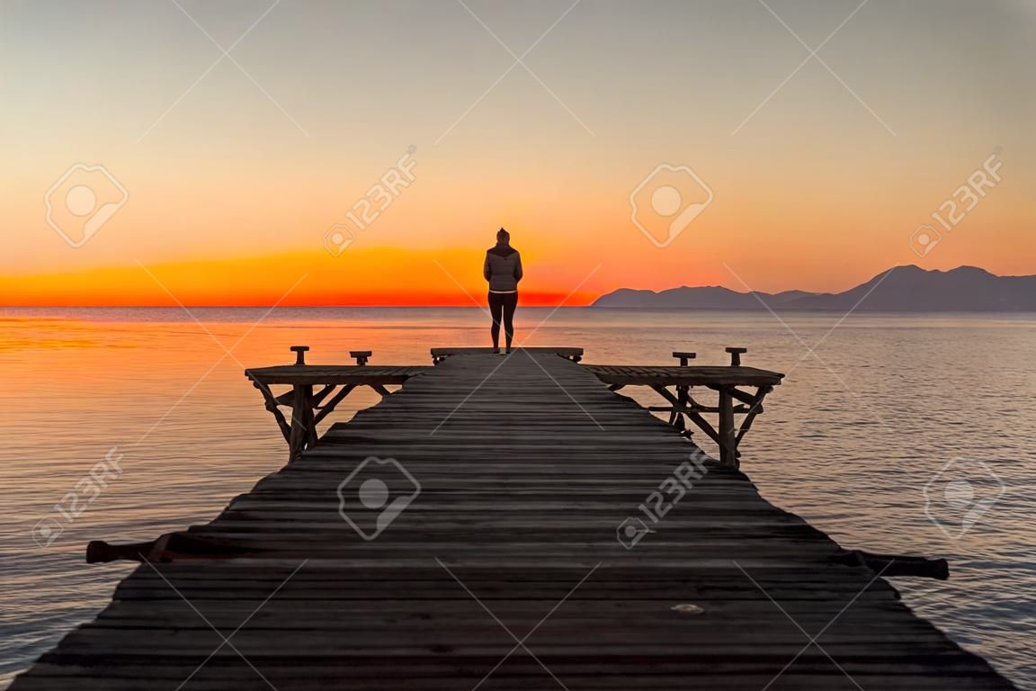 Alleen vrouw op de pier bij de zee in de zomer zonsopgang landschap