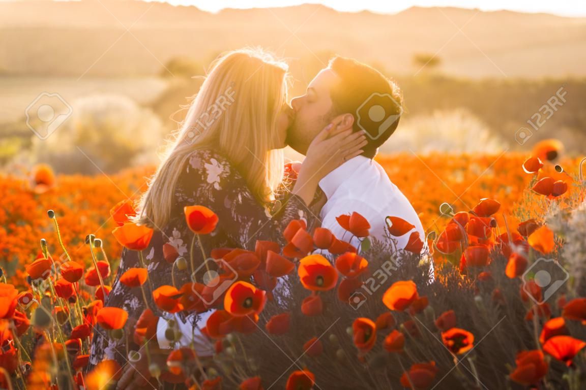 Man and woman embracing in poppy field on the dusk,  countryside Malta
