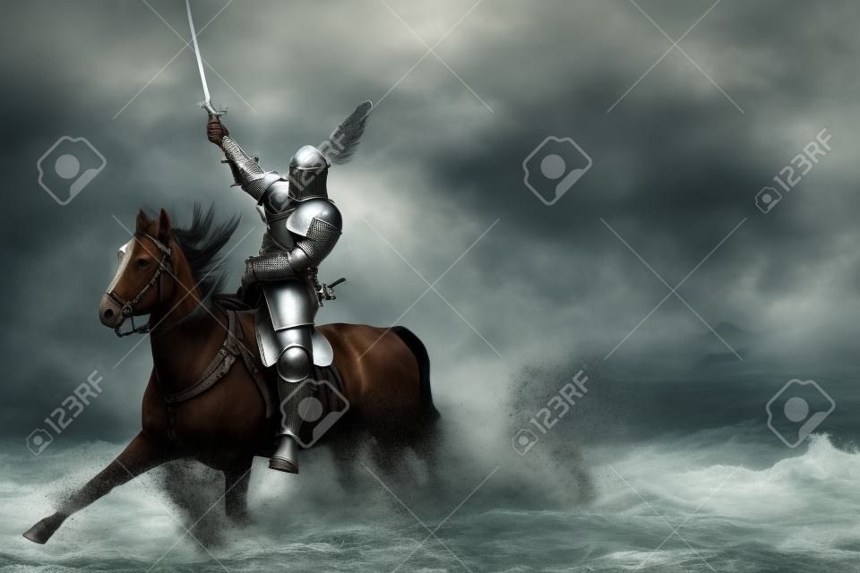 Un hombre adulto con una antigua armadura de caballero con una espada monta un caballo en un río a lo largo de una orilla de arena y posa
