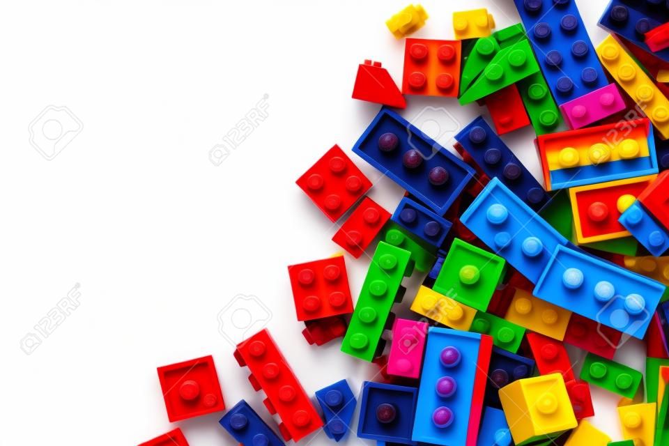 Close-up immagine di mattoncini lego colorati sparsi sul fianco di uno sfondo bianco