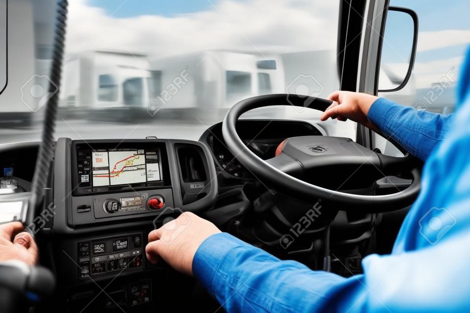 Kierowca ciężarówki jeździ jedną ręką i zmienia biegi, człowiek za kierownicą ciężarówki, skupienie na miejscu.