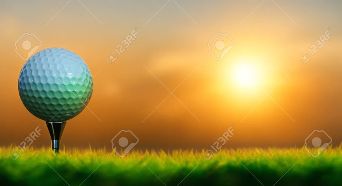 Een golfbal op zijn tee in een groene grasveld golfbaan met zonsopgang.