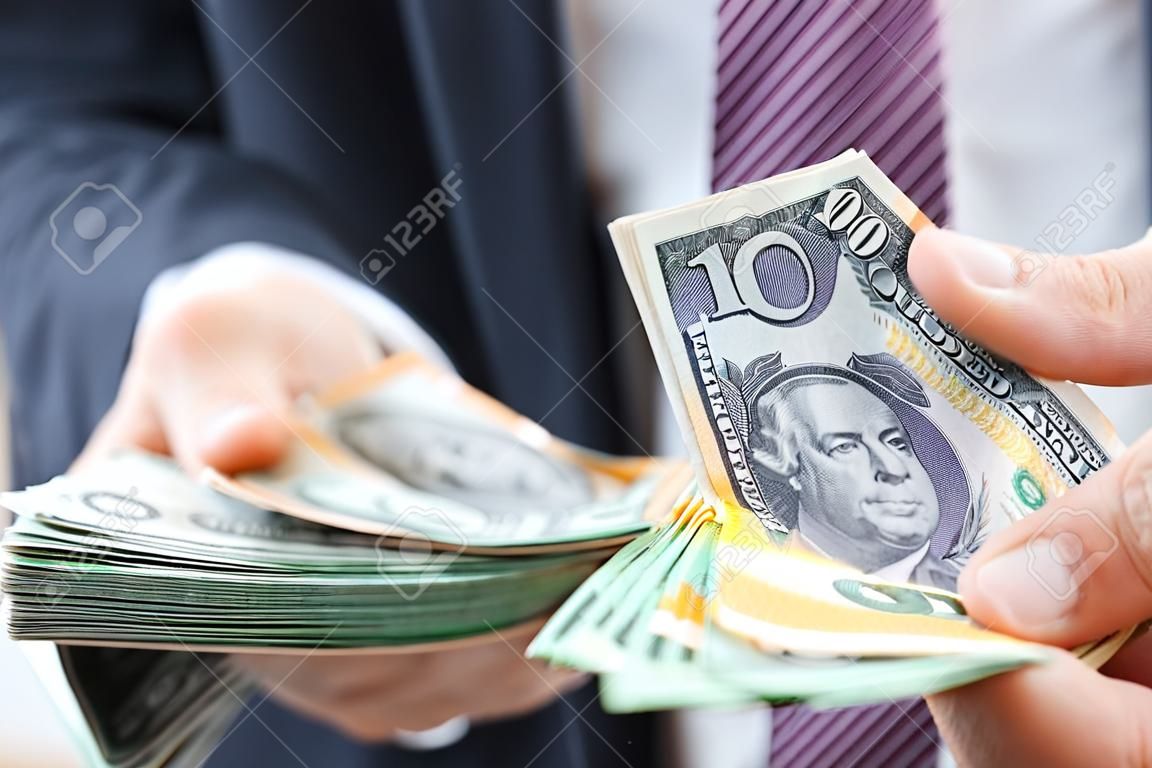 Money exchange and trading concept - hand holding Australian dollar (AUD) banknotes on blur background of businessman holding United States dollar (USD) bills,  about to swap