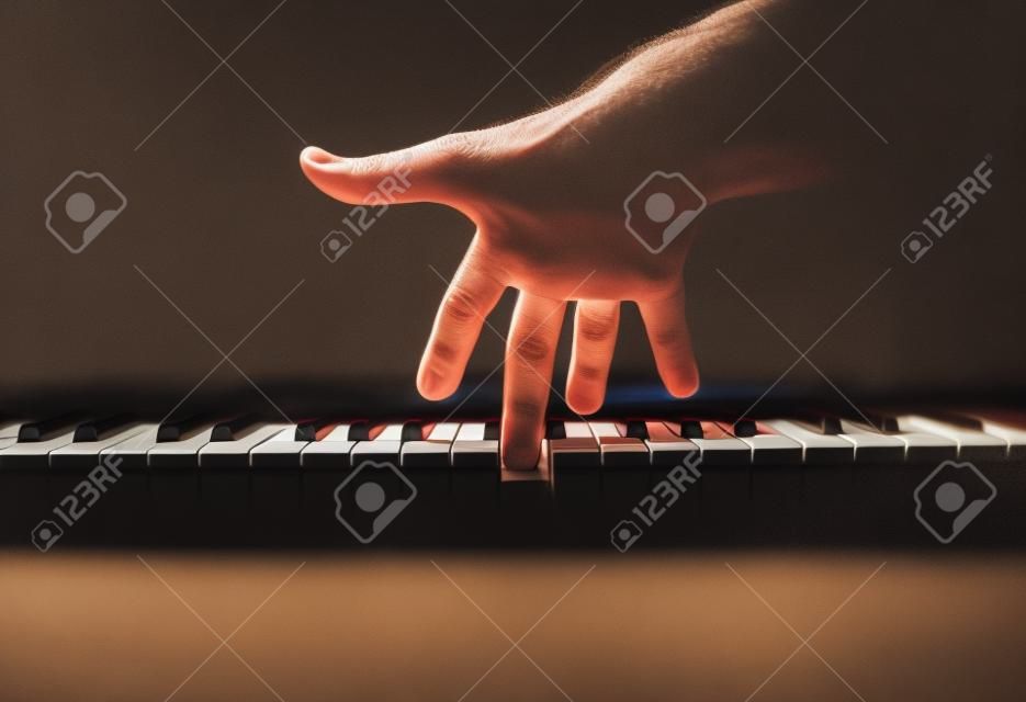 Playing a keyboard, one male hand playing, accentuated contrasts.