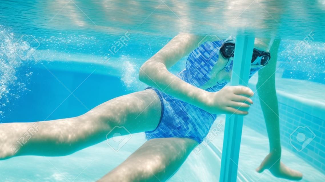 Underwater closeup photo of 10 years old girl swimming and diving in the swimming pool