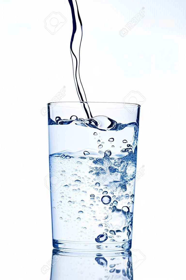 Wasser gießt in Glas auf weißem Hintergrund