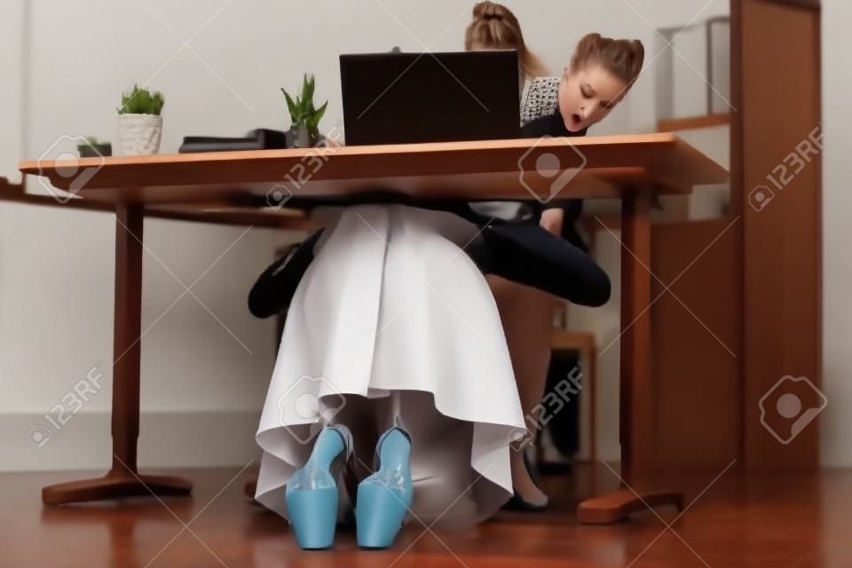 Young woman gives blowjob to boss under table