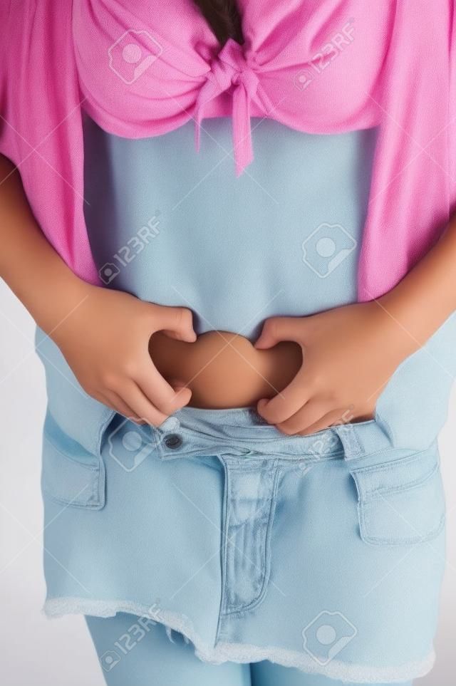 A young woman is holding the fat rolls on her stomach. 