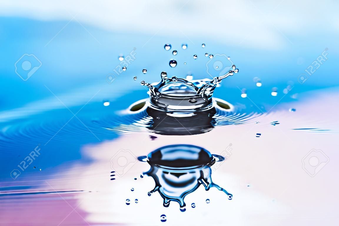 The drop of pure fresh water falls in water with splashes and vials