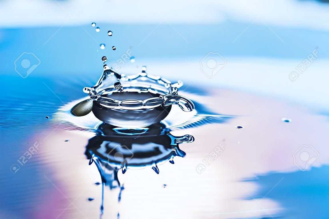 La gota de agua pura y fresca cae en el agua con salpicaduras y viales