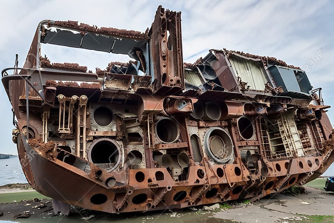 Enormes piezas oxidadas de un barco marino desmantelado que fue cortado y dejado en la orilla.