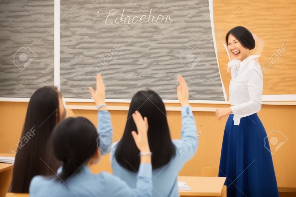 Teacher woman happy and young students who raised their hands is a lesson in class