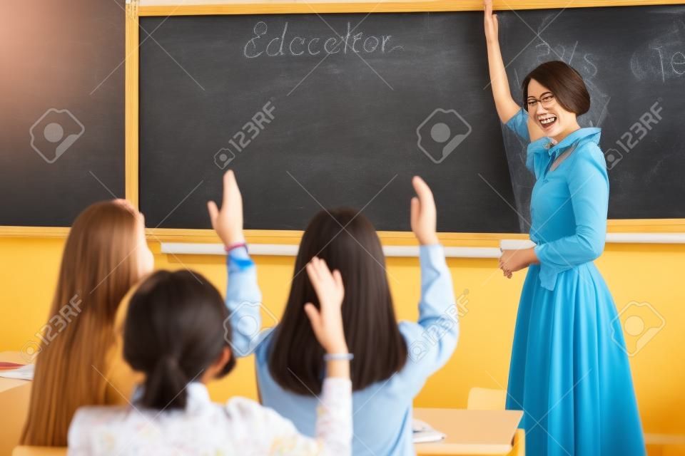 Teacher woman happy and young students who raised their hands is a lesson in class