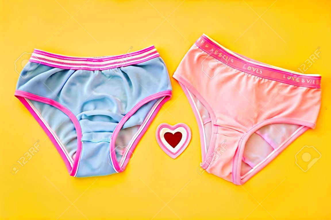 Blue and pink panties with a heart on a yellow background. The concept of meeting lovers. Underwear. The view from the top. Beautiful lingerie. Flat lay.