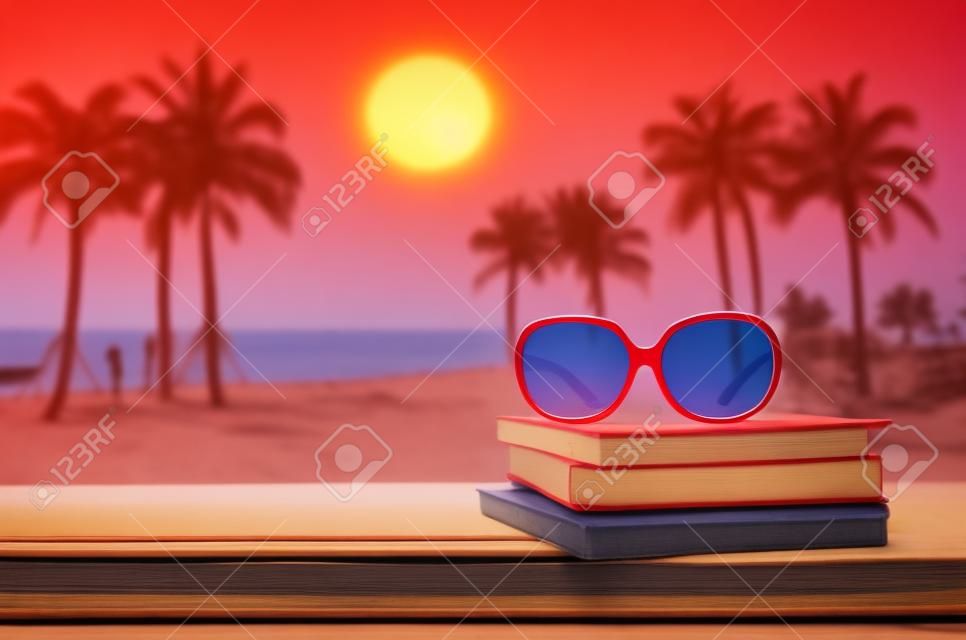 rode zonnebril op stapel boek met zeescape backgroud