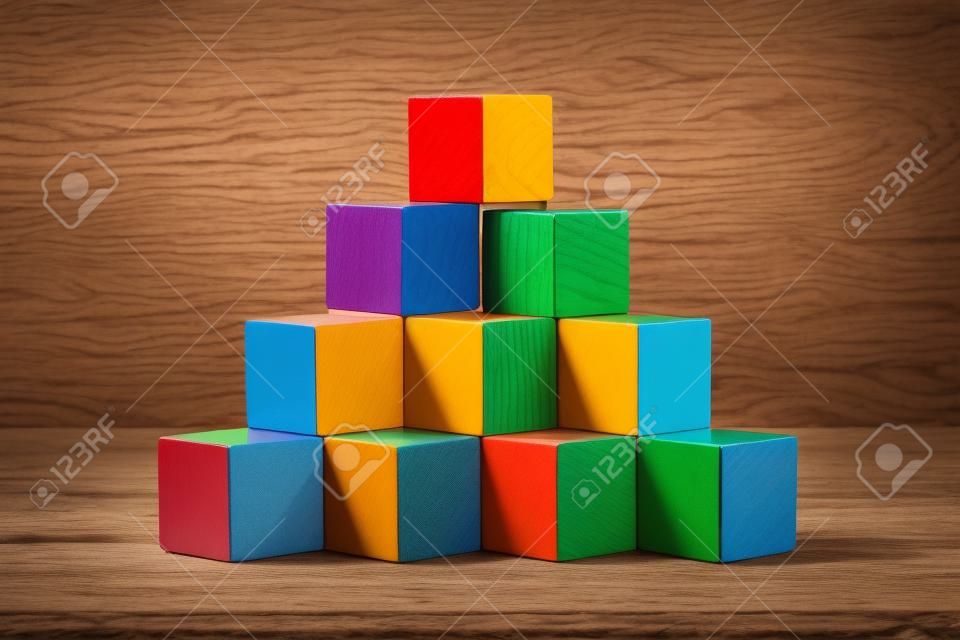 stack of colorful wood cube building blocks on wood background