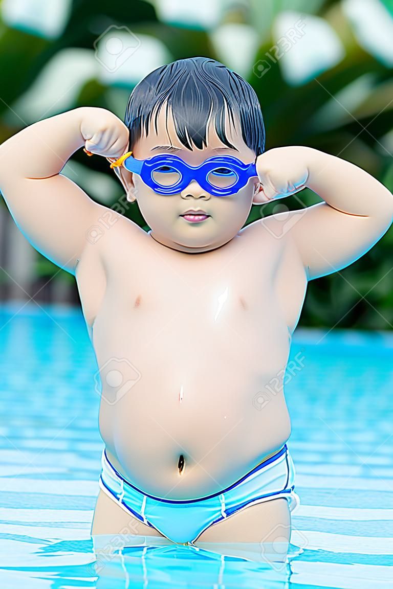 chico gordo asiático mostrándole muscular en la piscina.