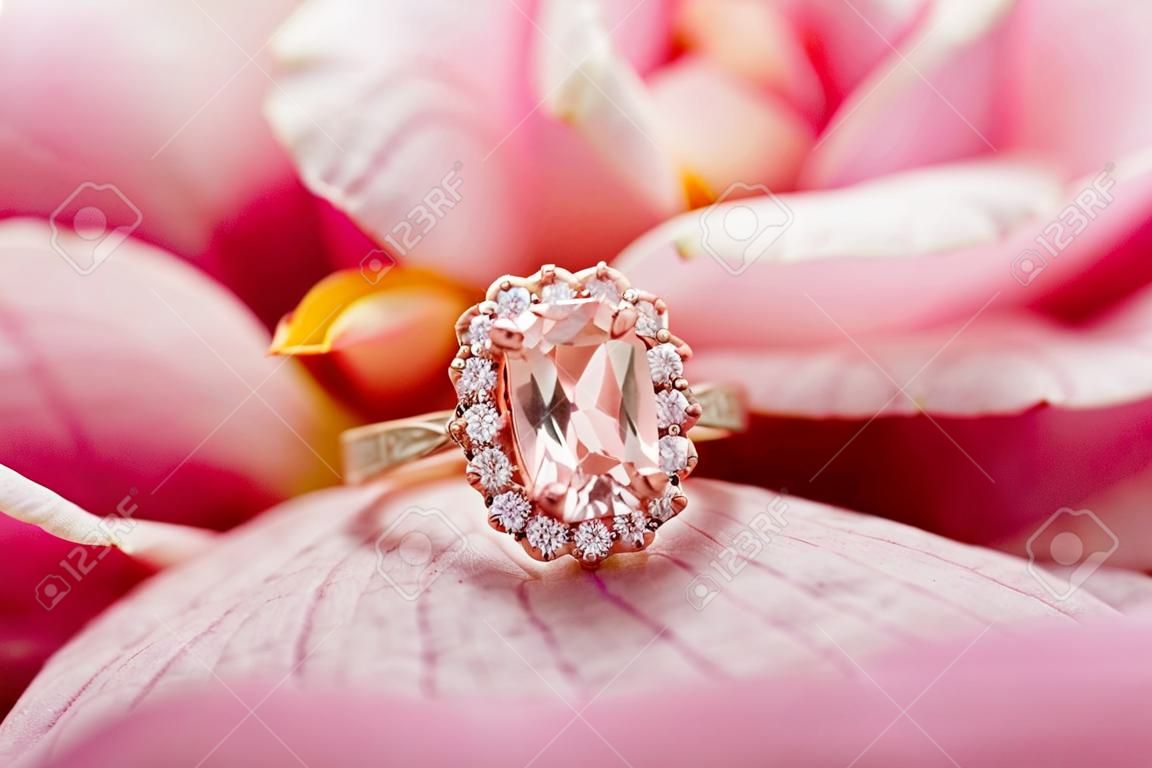 Schmuck rosa Diamantring auf schönem Rosenblütenhintergrund hautnah