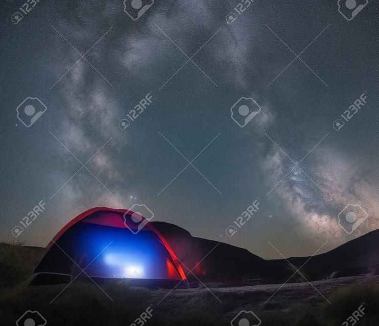Céu Nigt bonito com a pequena tenda da Via Láctea e um canyon vermelho do fogo do acampamento