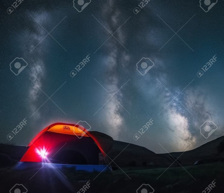 Céu Nigt bonito com a pequena tenda da Via Láctea e um canyon vermelho do fogo do acampamento