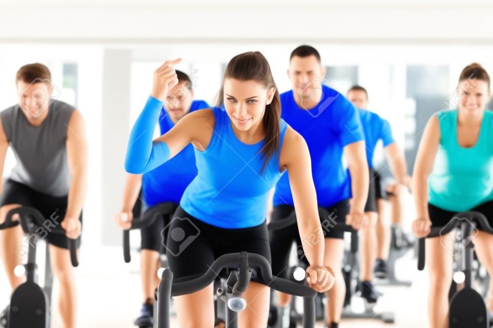 Groupe de cinq personnes, hommes et femmes - la filature dans le club de gym ou de fitness exercice de leurs jambes font de cardio-training, le formateur est en face
