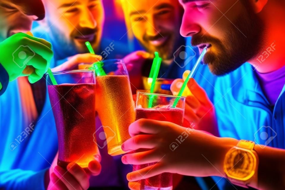 四個朋友喝蘇打水在酒吧與五顏六色的吸管