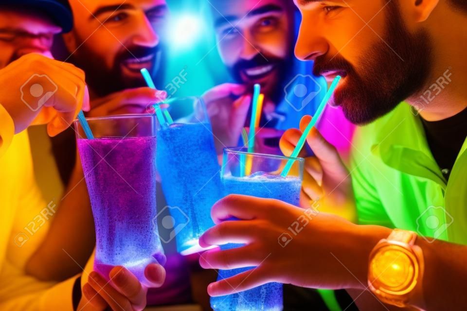 四個朋友喝蘇打水在酒吧與五顏六色的吸管