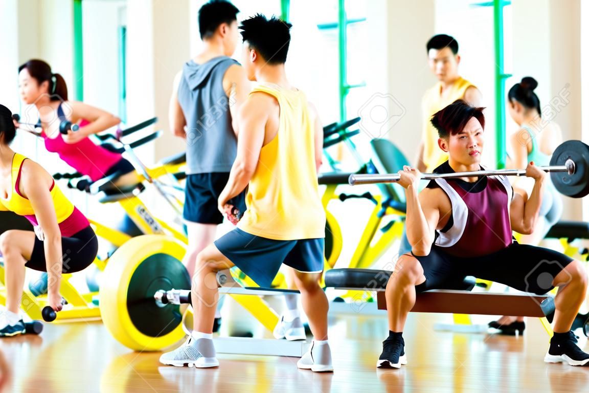 Chinesische asiatische Gruppe von Männern und Frau macht Sport Übungen oder Schulungen in Fitness-Studio mit Hantel Gewichte für mehr Leistung