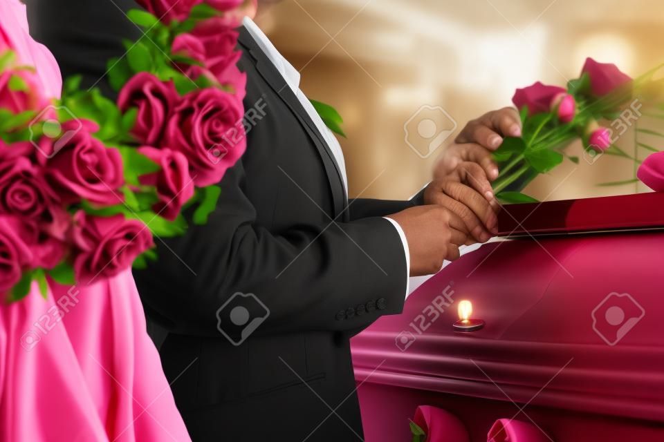 Deuil homme et femme sur funéraire avec rose rose debout au cercueil ou le cercueil