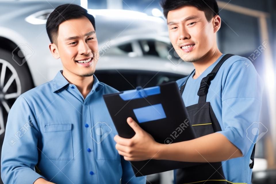 Asian meccanico di auto cinese con il cliente passa attraverso la lista di controllo di manutenzione
