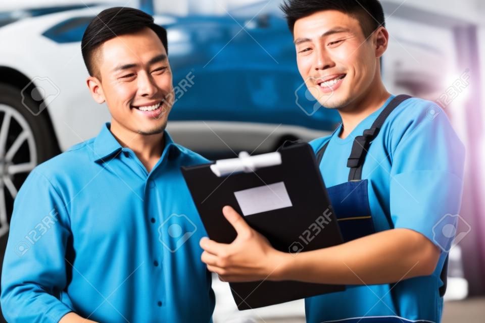 Asian meccanico di auto cinese con il cliente passa attraverso la lista di controllo di manutenzione