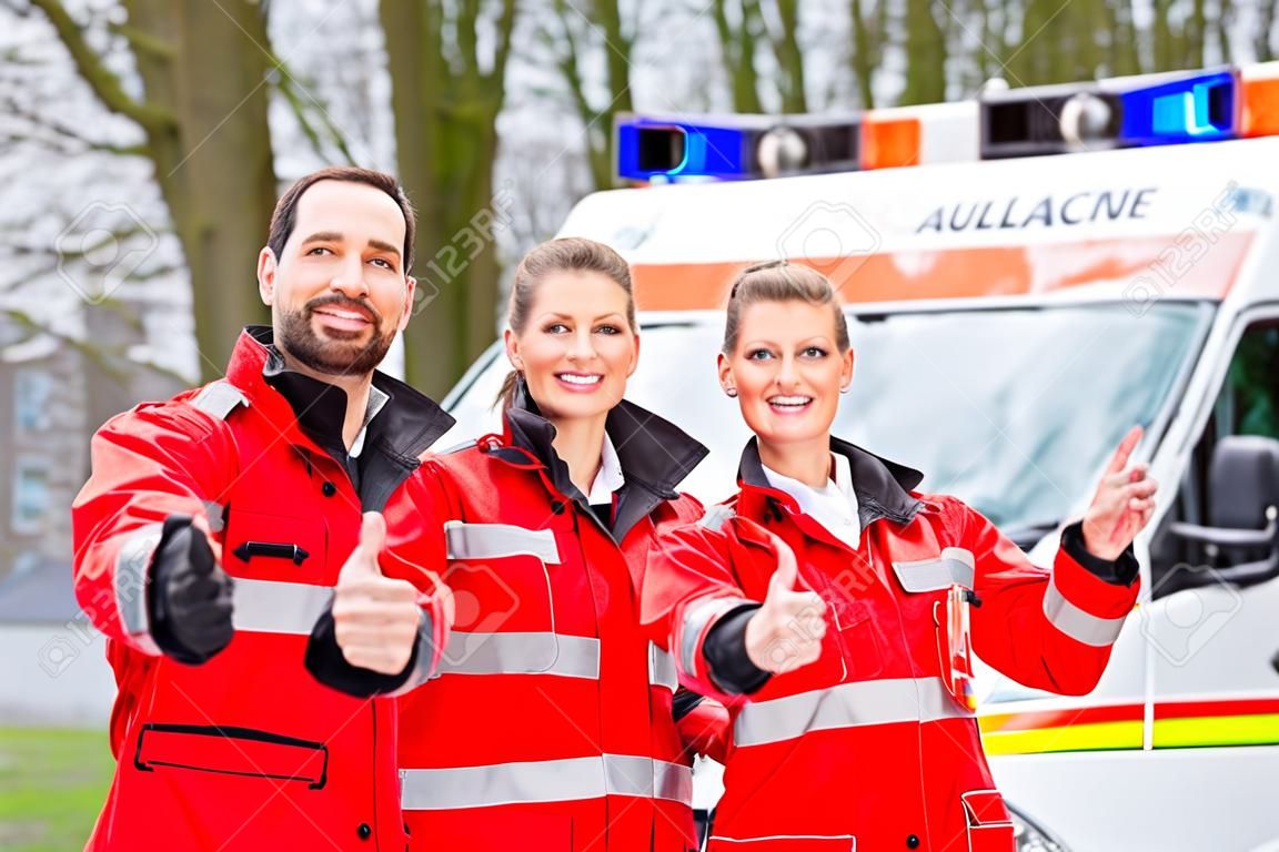 Médico de emergencia y la enfermera de pie delante de la ambulancia