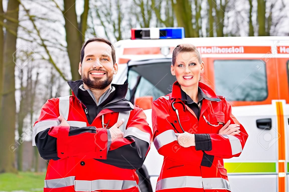 Médico de emergencia y la enfermera de pie delante de la ambulancia