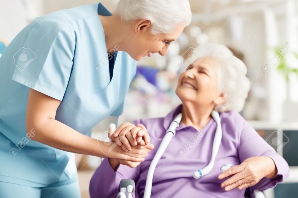 Nurse holding hand of senior woman in pension home