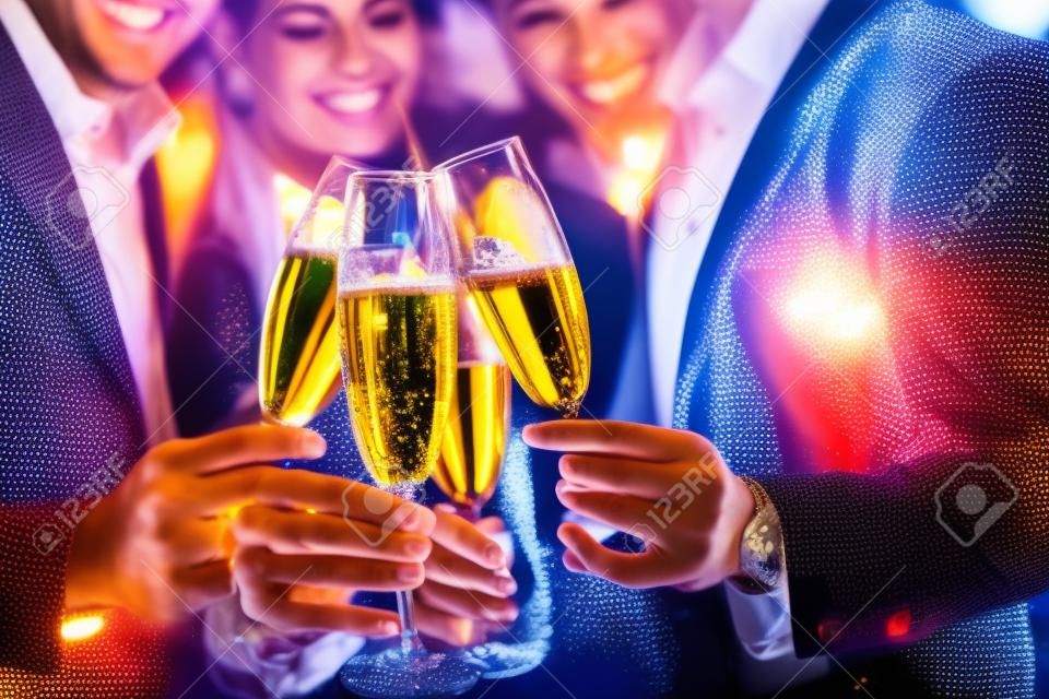 Férfiak és nők, akik születésnapot vagy új éveket ünneplek, miközben csillogó borokat csillognak