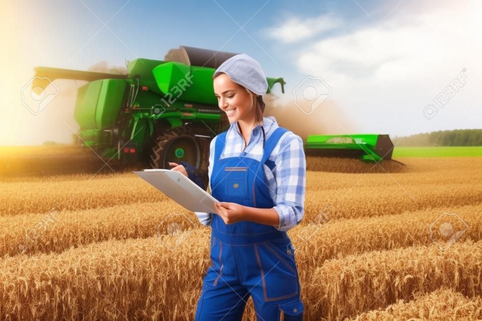 Agriculteur sur un champ pendant la récolte avec presse-papiers faisant le contrôle