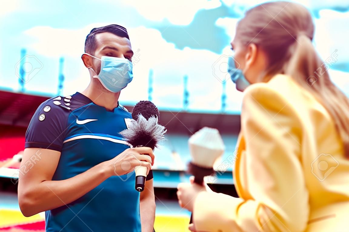 Journaliste faisant une interview avec un joueur de football pendant covid-19 portant des masques dans un stade de football