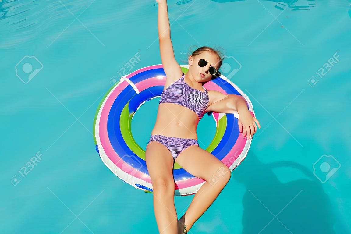 Девушка-подросток в кругу кольцо в воде у бассейна.