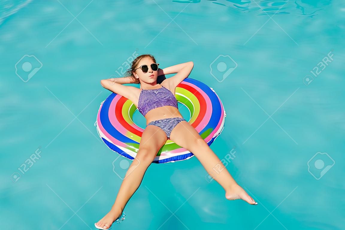 Девушка-подросток в кругу кольцо в воде у бассейна.
