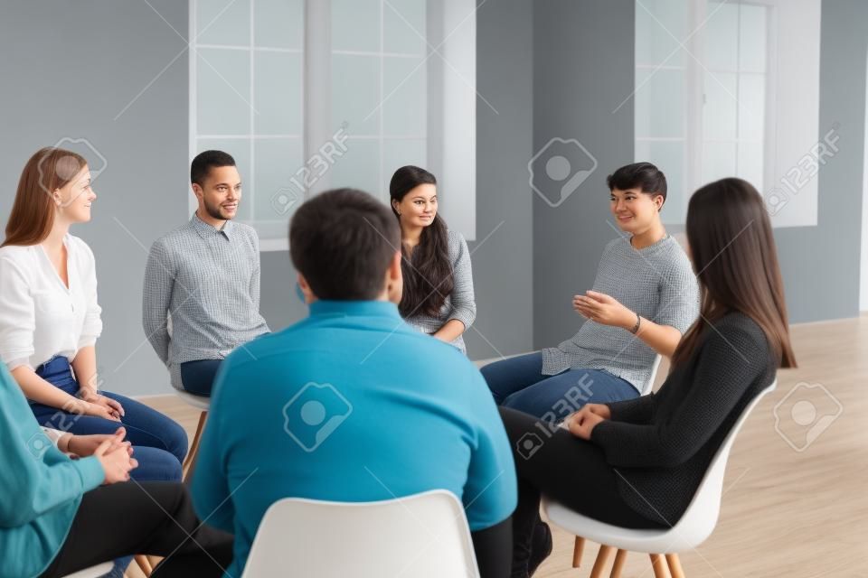 Diverse people listening to therapist sitting in circle in group therapy session. Patients talking, sharing concerns, coping with anxiety, dealing with psychological problems and insecurities together