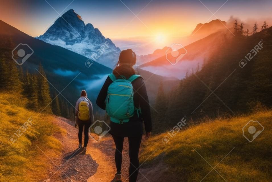 Excursionista de mujer con mochila de senderismo en senderos en las montañas al atardecer.
