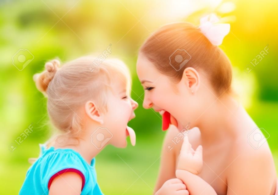 美麗的年輕母親和她的女兒在公園裡在陽光明媚的夏日開心和顯示舌頭（專注於女人）