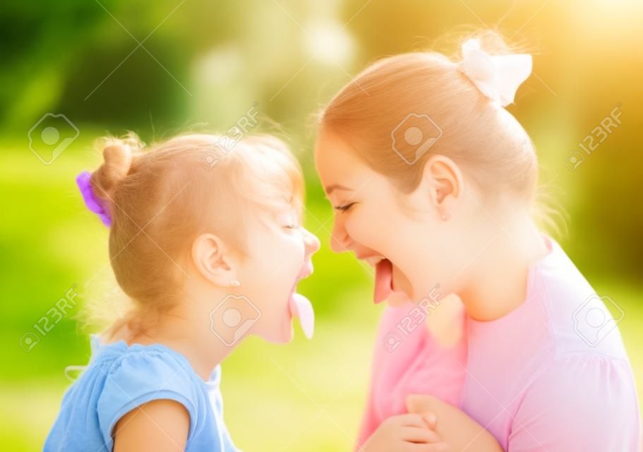 belle jeune mère et sa fille dans le parc sur une journée d'été ensoleillée en s'amusant et en montrant la langue (accent mis sur la femme)