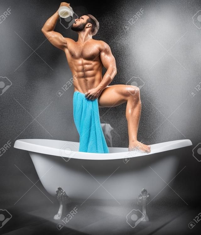 atraente musculoso jovem homem tomando um banho com leite