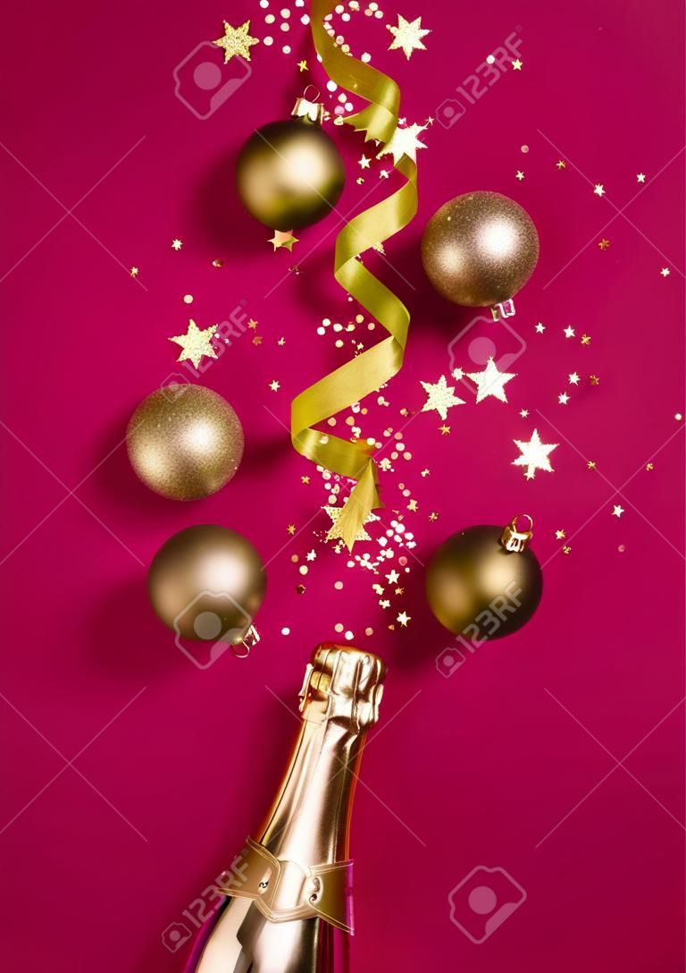 Luxury Christmas composition with golden champagne bottle and decorations on trendy magenta background in flat lay style. Christmas or New Year Eve celebration concept. Holiday card.
