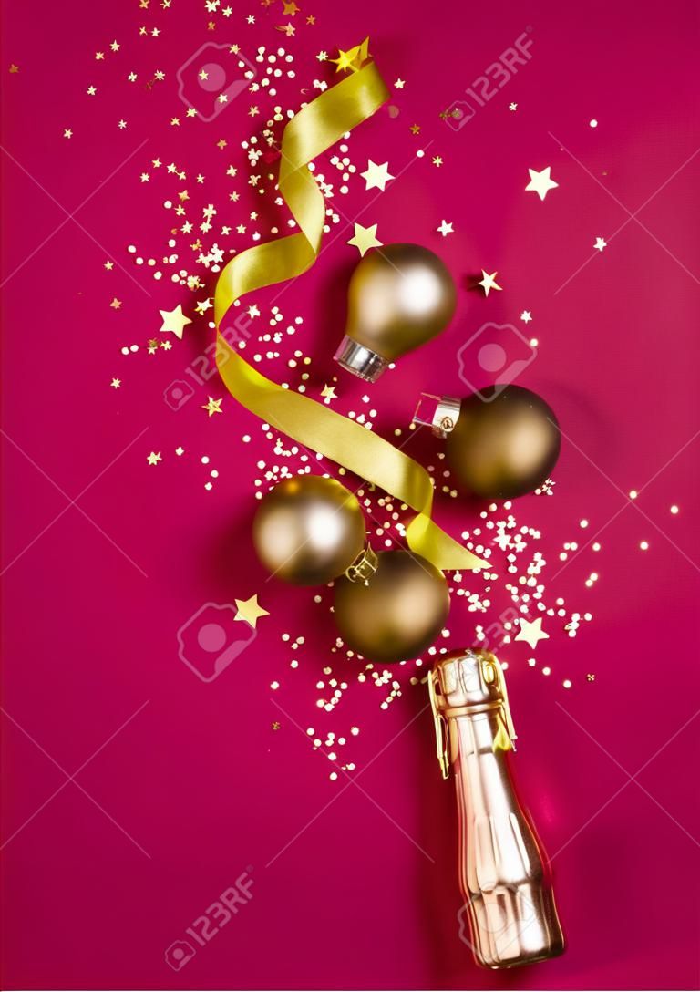 Luxury Christmas composition with golden champagne bottle and decorations on trendy magenta background in flat lay style. Christmas or New Year Eve celebration concept. Holiday card.