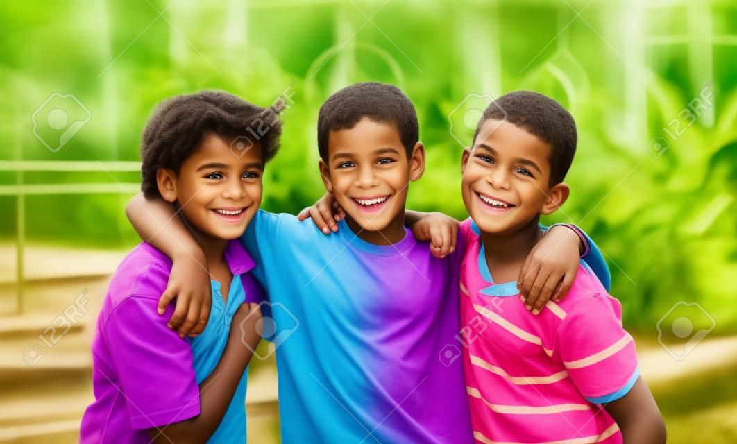 Retrato de tres niños sonrientes guapos de diferentes razas en el exterior.