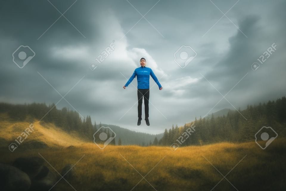 mężczyzna lewitujący przed wzgórzami